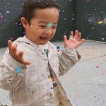 Young kid with Down Syndrome laughing with confetti. DSIA Providing Down Syndrome Support in Sacramento and Surrounding areas.